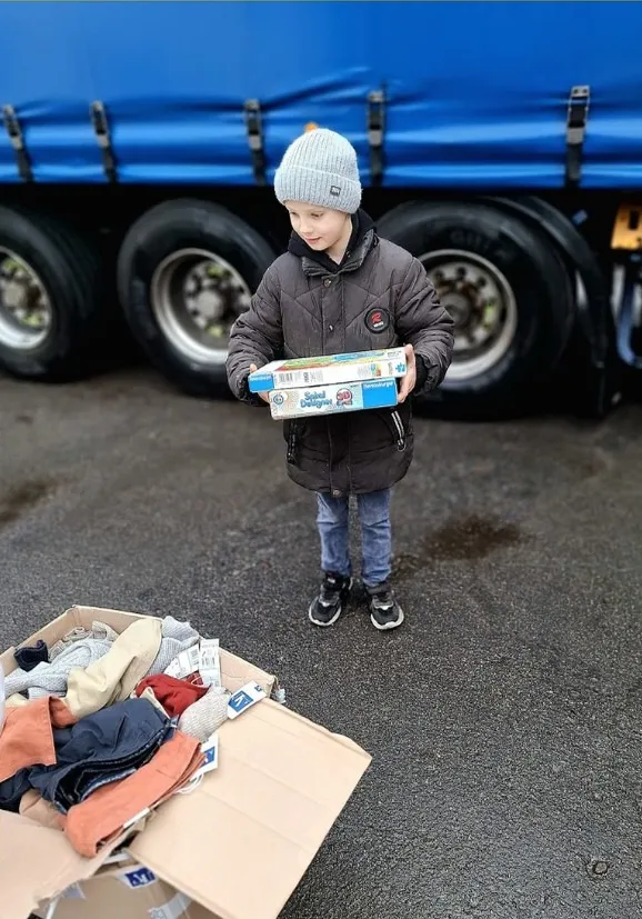 Un jeune garçon reçoit un colis lors d'une distribution
