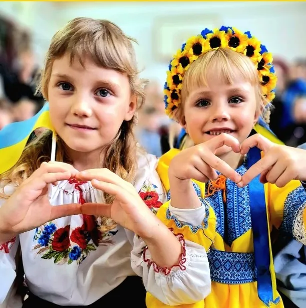 Deux fillettes ukrainiennes en tenue traditionnelle font un cœur avec leurs mains